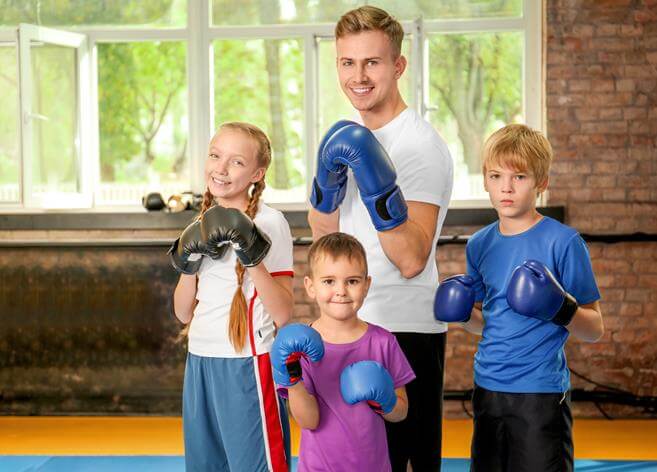 malenkie deti v bokserskih perchatkah s trenerom